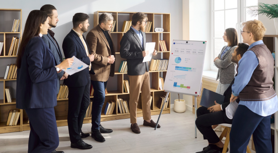 Business team attending a presentation and discussing charts in a meeting room.