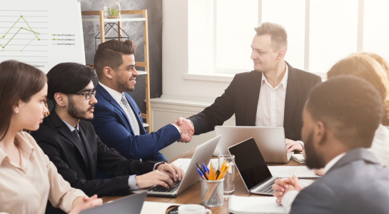 Business professionals shaking hands during a meeting at a conference table.