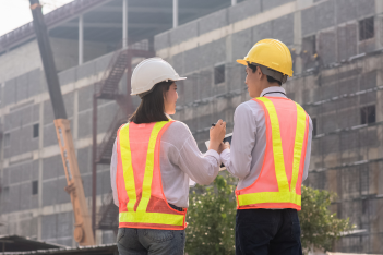 Construction workers in safety vests discussing a project at a building site.