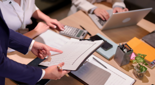Team reviewing financial reports and calculations at an office desk.