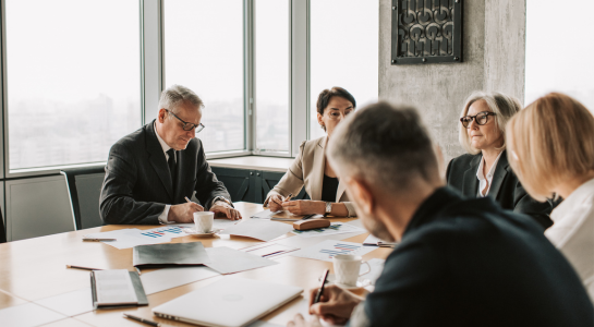 Senior executives reviewing reports during a business meeting in a conference room.