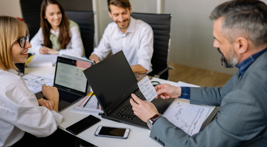 Team collaborating around laptops and documents during a business meeting.