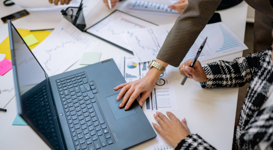 Colleagues analyzing charts and financial data on a laptop during a meeting.