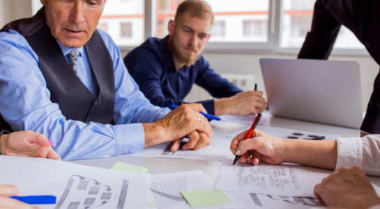 Business team reviewing documents and discussing plans during an office meeting.