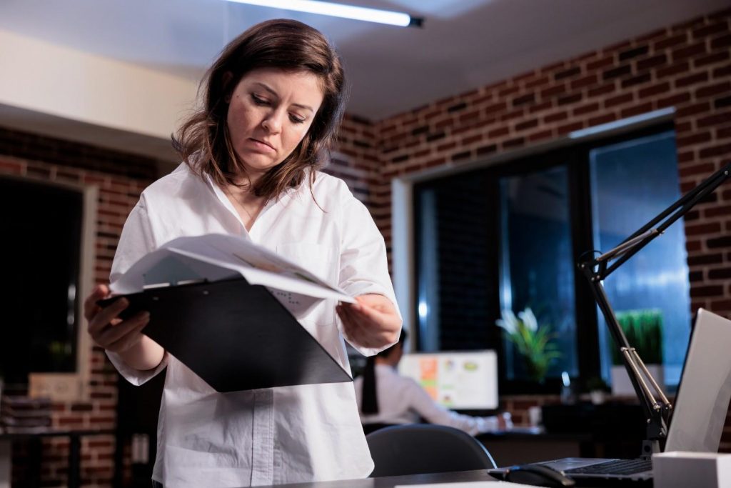 Woman reviewing documents on a clipboard while working in an office.