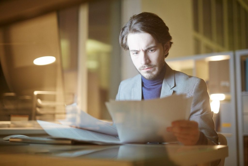 Man reviewing paperwork at a desk in a modern office.